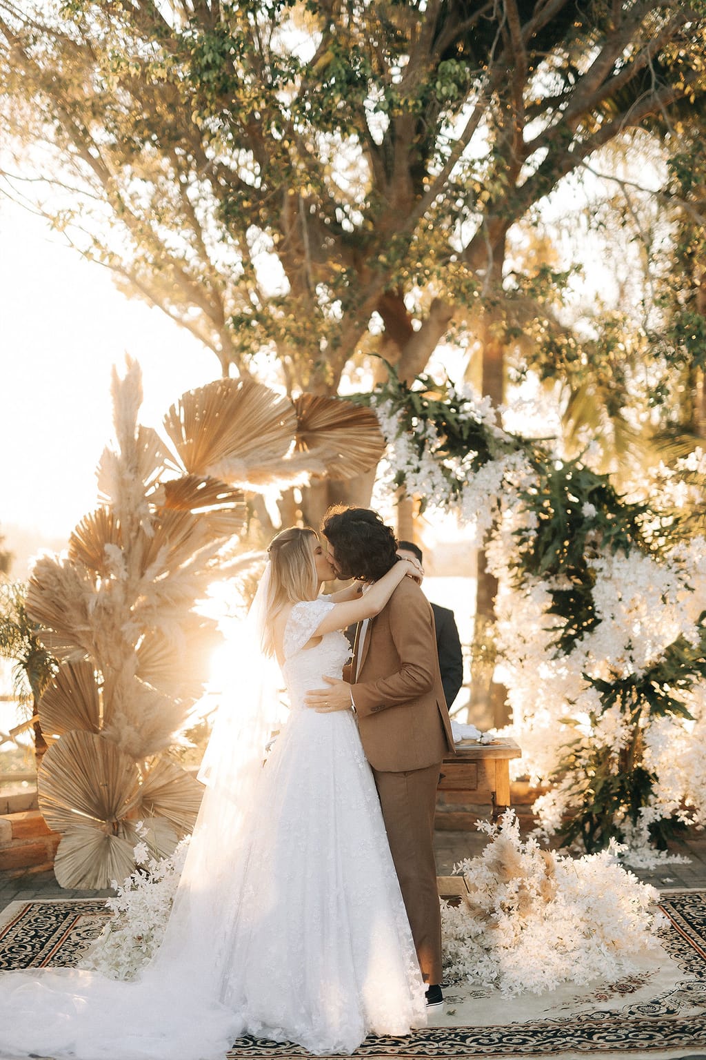 Mychelle e Fábio abraçados no altar decorado com capim-dos-pampas na golden hour