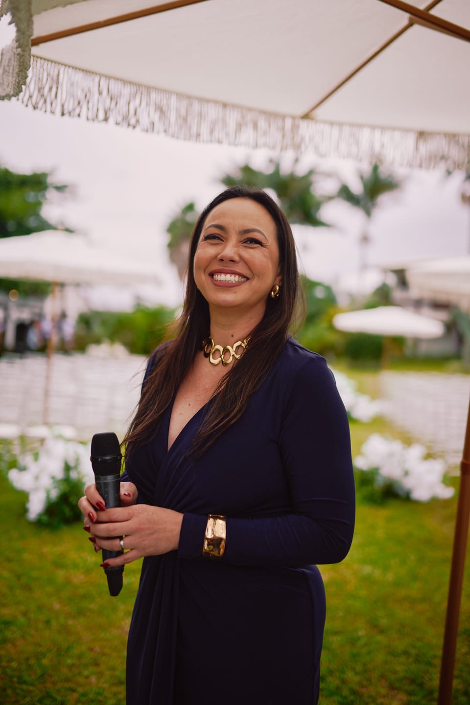 Michelle sorrindo ao microfone enquanto celebra uma cerimônia ao ar livre