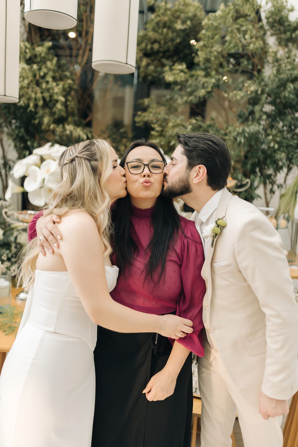 Taiana e Bruno beijando as bochechas de Michelle ao mesmo tempo, os três sorrindo